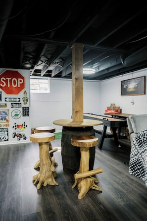 A room with a wooden table and stools, a stop sign on the wall, and a window.