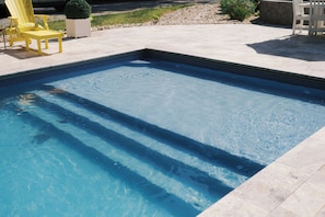 A rectangular swimming pool with clear blue water, surrounded by a tiled deck.