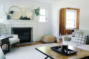 A living room with a fireplace, a sofa, a chair, a coffee table, and a wooden wall.