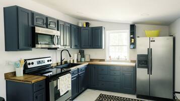 Una cucina moderna con mobili blu scuro, elettrodomestici in acciaio inossidabile e una finestra che lascia entrare luce naturale.