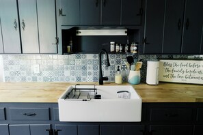 Een keuken met een witte spoelbak, donkere kastjes en een spatwand met een patroon van tegels.