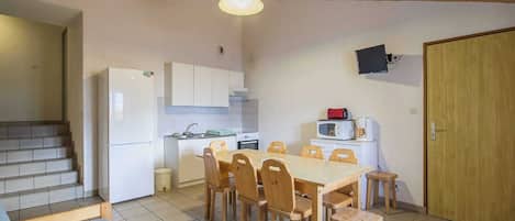Una cocina compacta con armarios blancos, una mesa de comedor de madera con seis sillas, un microondas y un tostador.