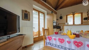 Eine gemütliche Küche mit Holztisch, Fernseher und Frühstücksecke.