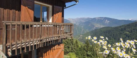 Una cabaña de madera con balcón y vistas a un paisaje montañoso.