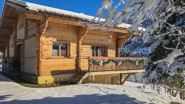 A wooden chalet with a balcony, surrounded by snow-covered trees and mountains. - CHALET LES AROLLES - HAUTELUCE LES SAISIES (HAUTELUCE LES SAISIES)