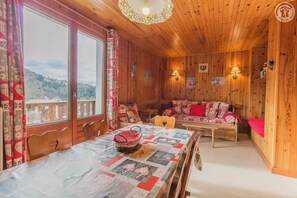 Enjoy a serene mountain view from the large window, with a comfortable sofa and dining area for relaxing and socializing.
