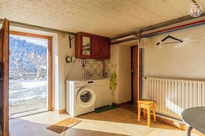 Enjoy a functional kitchen with a washing machine, dining table, and large window offering a view of the surrounding landscape.