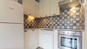 Eine Küche mit weißen Schränken, einem Geschirrspüler von Bosch und einem Edelstahlbackofen.