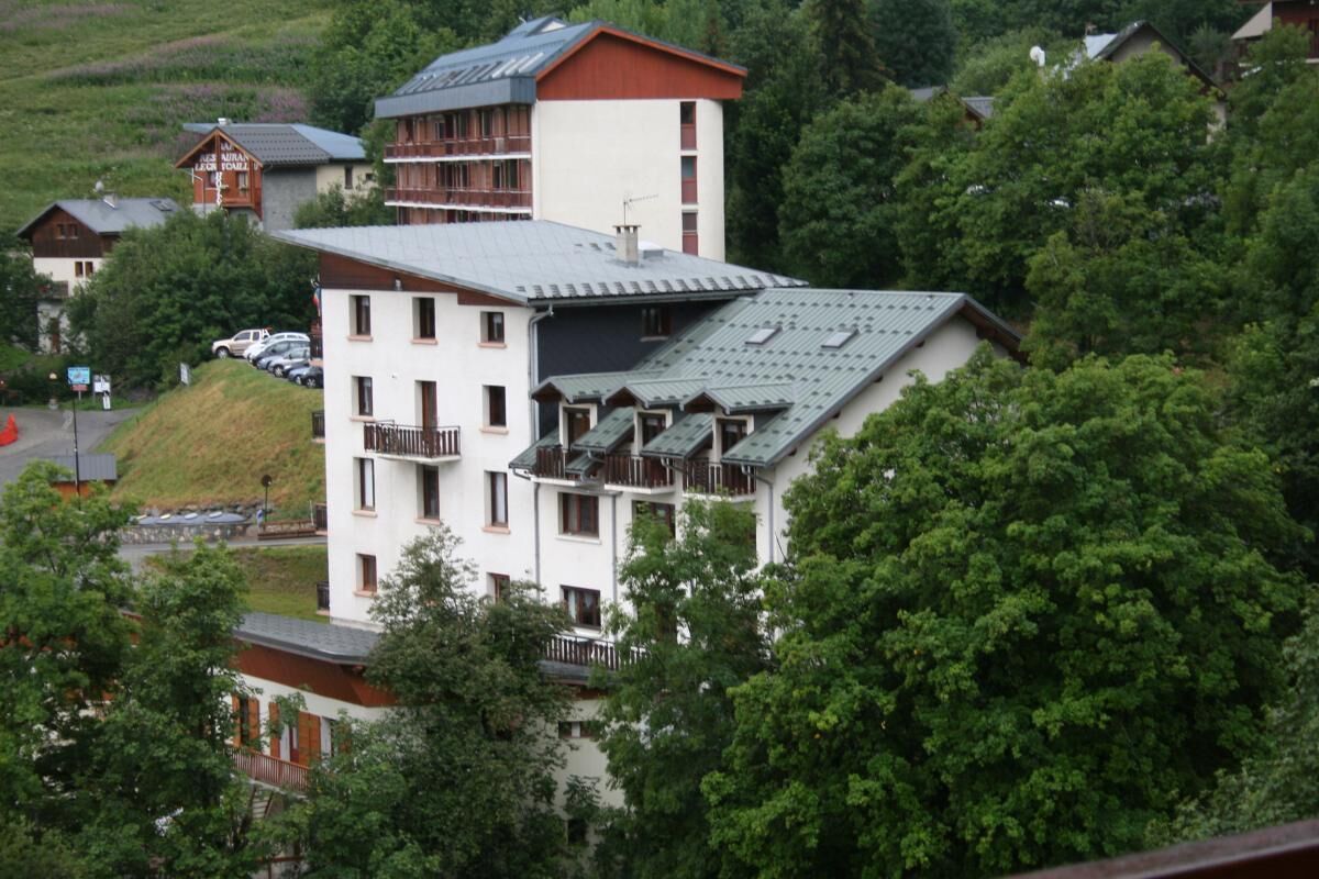 A multi-story building with balconies, surrounded by lush greenery.