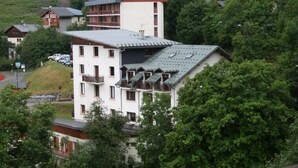 Ein mehrstöckiges Gebäude mit Balkonen, umgeben von üppiger Vegetation.