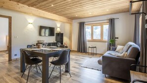Un intérieur moderne comprenant un coin repas, un canapé et un téléviseur fixé au mur.