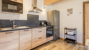 Une cuisine moderne avec des meubles en bois, un réfrigérateur en acier inoxydable, un four encastré et une machine à café.