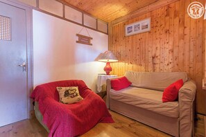 Cozy room with a door, sofa, and chair, featuring a table lamp and framed picture.
