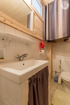 Bathroom with a sink, toilet, and storage shelf.