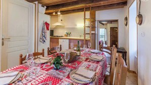 A dining area with a table set for four, a kitchen in the background, and a wooden ceiling. - CHEZ MARIE - LA TRINITE (LA TRINITE)