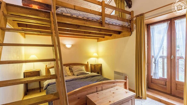 A wooden bunk bed with a ladder, a bedside table with a lamp, a wooden dresser, and a window with curtains. - CHEZ MARIE - LA TRINITE (LA TRINITE)