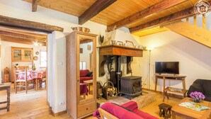 A cozy living room with a wooden ceiling, a fireplace, a sofa, and a dining area with a table and chairs. - CHEZ MARIE - LA TRINITE (LA TRINITE)