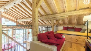 A wooden interior with a sofa and a bed, a dining area with a table and chairs, and a view through a balcony. - CHALET AKENE - SAINTE FOY TARENTAISE (STE-FOY-TARENTAISE)