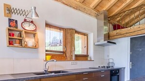 A modern kitchen with wooden cabinets, a black countertop, and a window with a view of the outdoors. - CHALET AKENE - SAINTE FOY TARENTAISE (STE-FOY-TARENTAISE)
