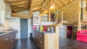 A modern kitchen with dark tiles, wooden cabinets, and a central island with various appliances. - CHALET AKENE - SAINTE FOY TARENTAISE (STE-FOY-TARENTAISE)