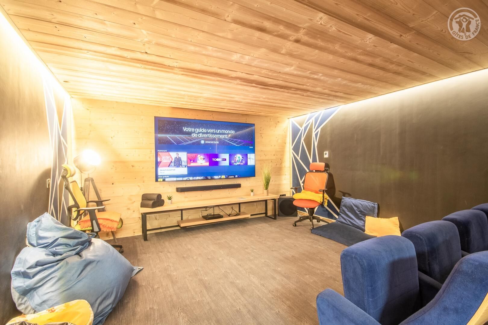 Une pièce chaleureuse avec un grand écran de télévision, des murs en bois et des sièges confortables.
