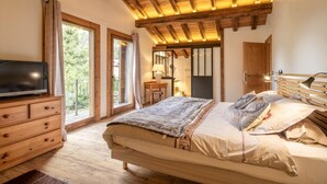 A bedroom with a wooden ceiling, a bed with pillows, a TV on a wooden dresser, and large windows. - CHALET LE COURTI - SAINTE FOY TARENTAISE (SAINTE FOY TARENTAISE)