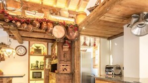 A rustic kitchen with wooden beams, a tiled floor, and various kitchen utensils. - CHALET LE COURTI - SAINTE FOY TARENTAISE (SAINTE FOY TARENTAISE)