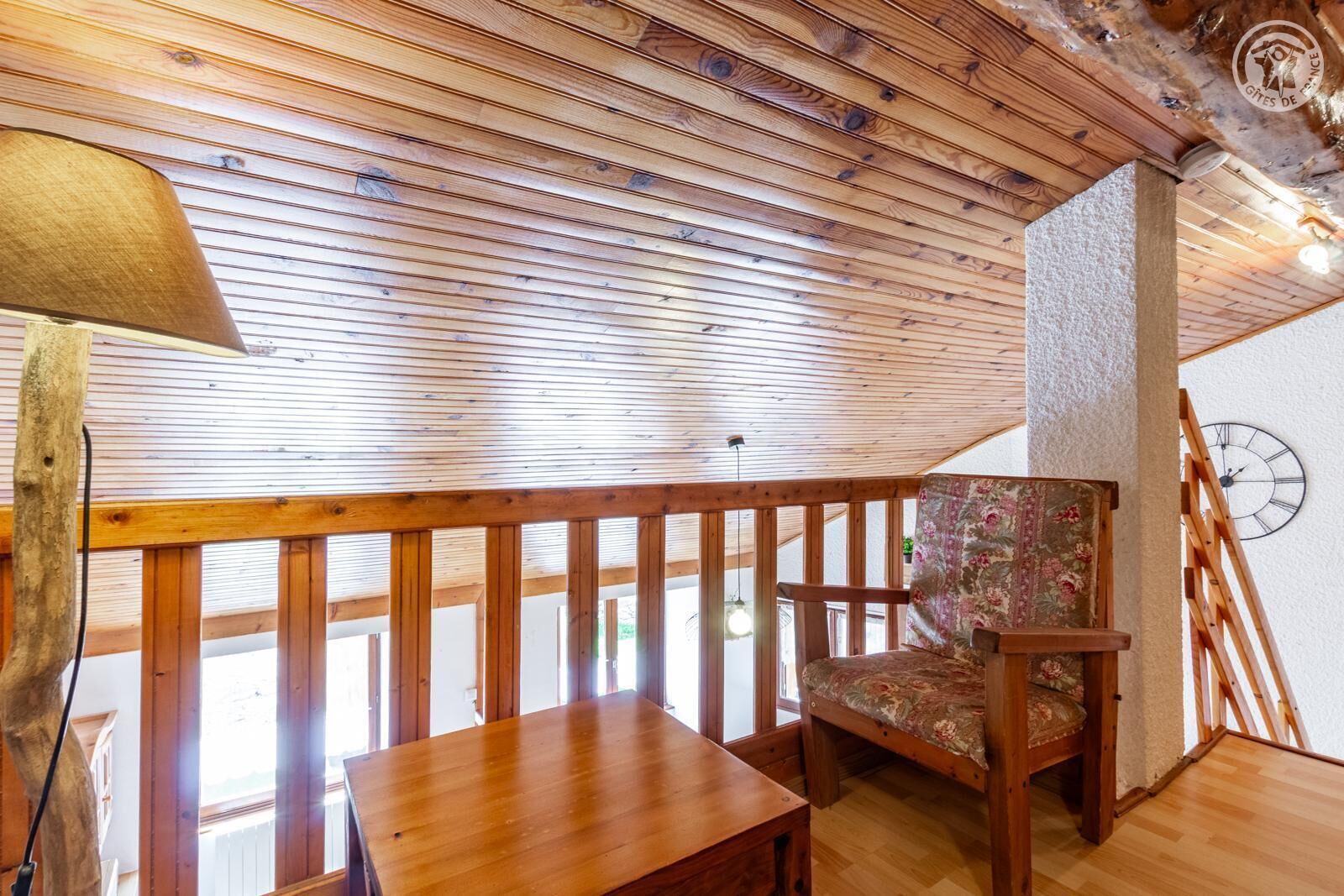 A wooden ceiling, a wooden chair, a wooden table, and a clock on the wall.