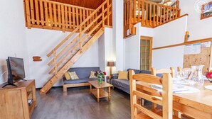 A wooden interior with a staircase, a sofa, a dining table, and a TV. - Symphorose - Larch (VAL-CENIS)