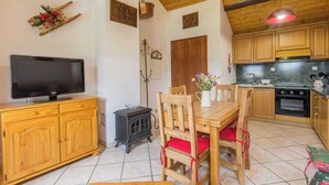 A cozy kitchen with wooden cabinets, a stove, and a dining area with a table and chairs. - L'ORCHIS VANILLÉ - VAL-CENIS (VAL-CENIS)