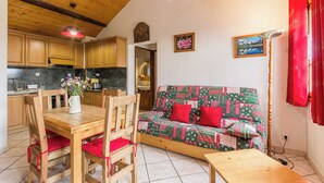 A cozy living room with a wooden ceiling, a dining table with chairs, a sofa with red cushions, and a red lamp. - L'ORCHIS VANILLÉ - VAL-CENIS (VAL-CENIS)