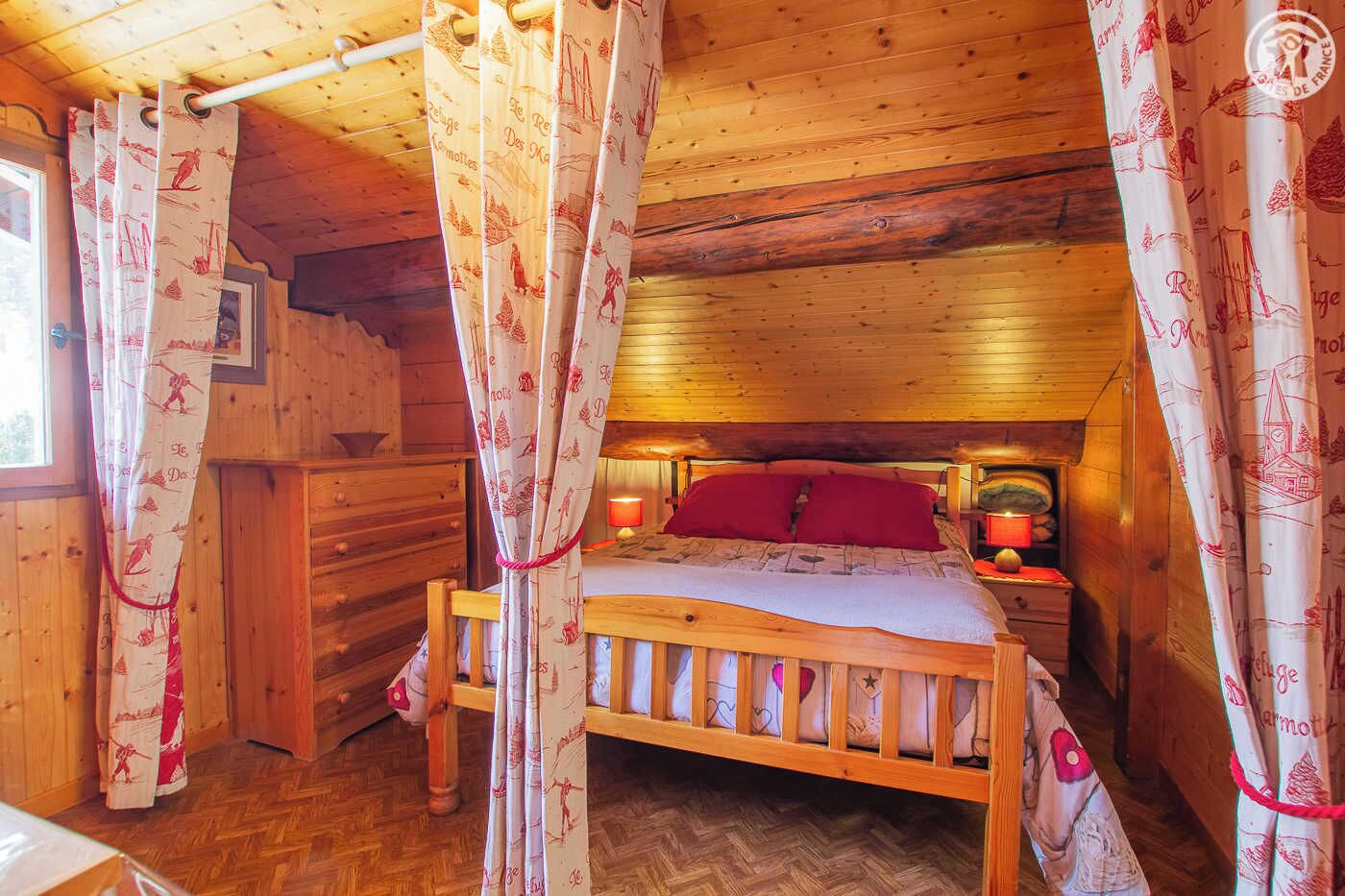 A wooden cabin bedroom with a bed, curtains, and a nightstand.