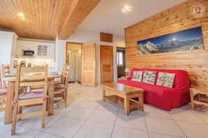Relax in this inviting living area with a sofa, dining table, and kitchen in the background.