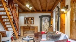 Un salon chaleureux avec un escalier en bois, une cheminée et un coin salon confortable.