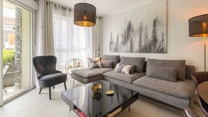 Relax in this stylish living room with a sofa, armchair, and dining table, surrounded by a beautiful forest view.