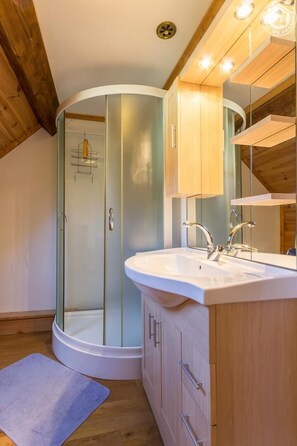 Enjoy a refreshing shower in the bathroom with a glass-enclosed shower area, a sink, and wooden cabinetry.