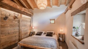 A cozy bedroom with a wooden bed, a small window, and a decorative wall piece.