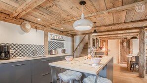 A kitchen with a central island, bar stools, a coffee machine, and a microwave.