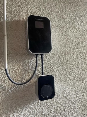 An EV charging station with a cable connected to a wall socket.