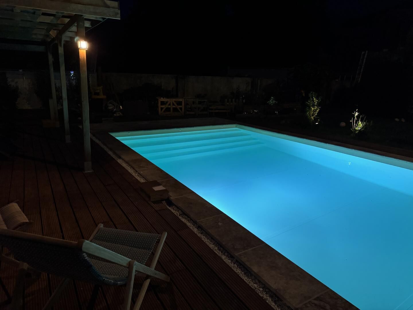 A swimming pool with a wooden deck and a covered seating area.