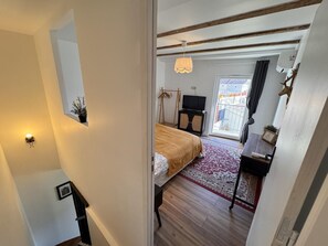 A bedroom with a bed, a television, a small table, and a window with a view of buildings. - La Cigale Et La Fourmi - The Pigeon House (AIX LES BAINS)