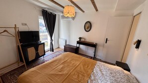 Una camera da letto con un letto, una scrivania, una sedia, un lampadario e una finestra con tende.