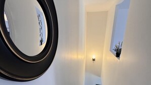 Una scala con ringhiera in legno, uno specchio fissato al muro e una piccola pianta in vaso.