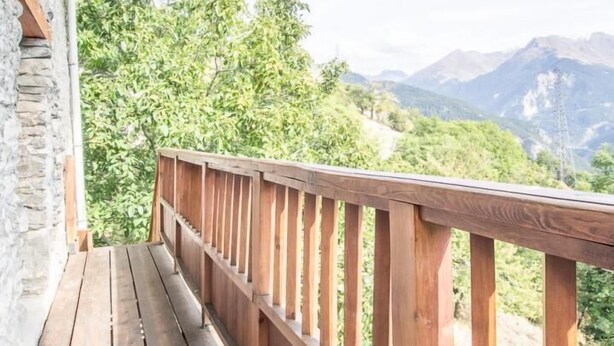 A wooden deck with a railing overlooking a mountainous landscape.