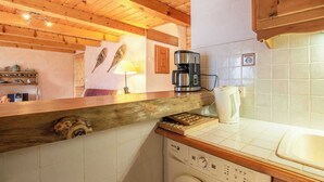 A kitchen with wooden beams, a coffee maker, a kettle, and a washing machine.