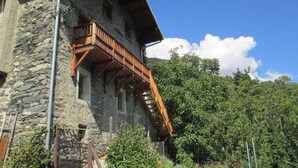 A stone building with a wooden balcony and a staircase leading to the upper floor.