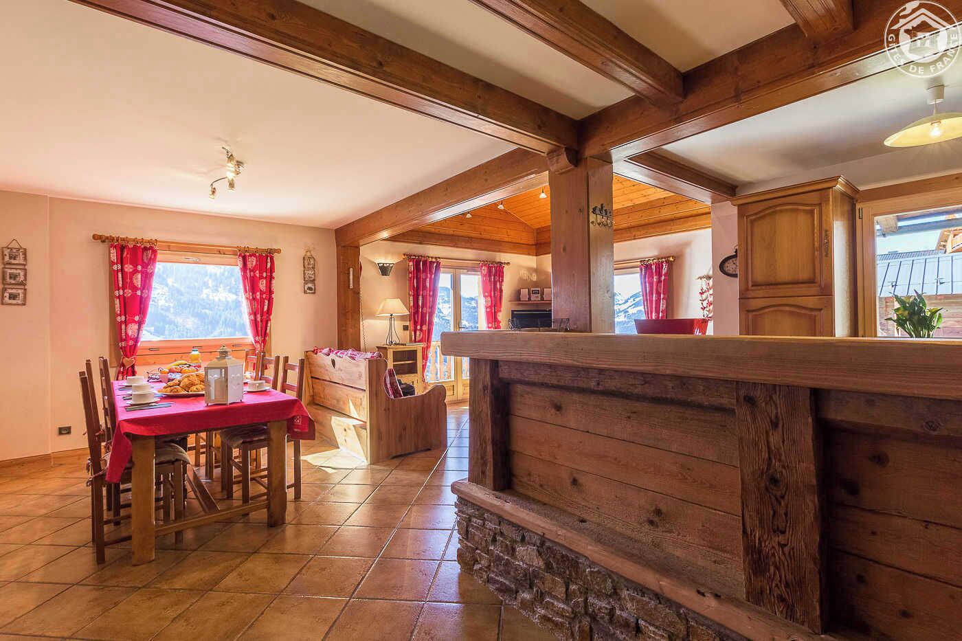 Un intérieur chaleureux en bois, comprenant un coin repas, une cuisine et une vue sur l’extérieur.