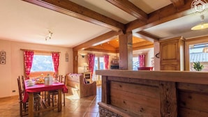 A cozy wooden interior with a dining area, a kitchen, and a view of the outdoors. - CHALET LA RUIDE - HAUTELUCE LES SAISIES (HAUTELUCE LES SAISIES)