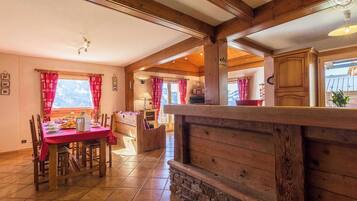 Un intérieur chaleureux en bois, comprenant un coin repas, une cuisine et une vue sur l’extérieur.