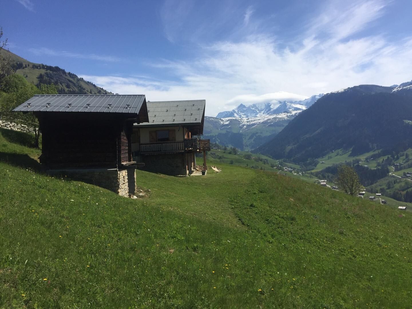 Un chalet doté d’un balcon donnant sur une vallée et des montagnes.
